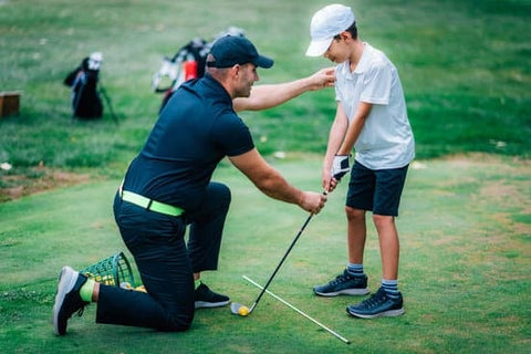 boy taking a golf lesson from golf instructor